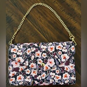 A contemporary floral print clutch with a gold chain strap.